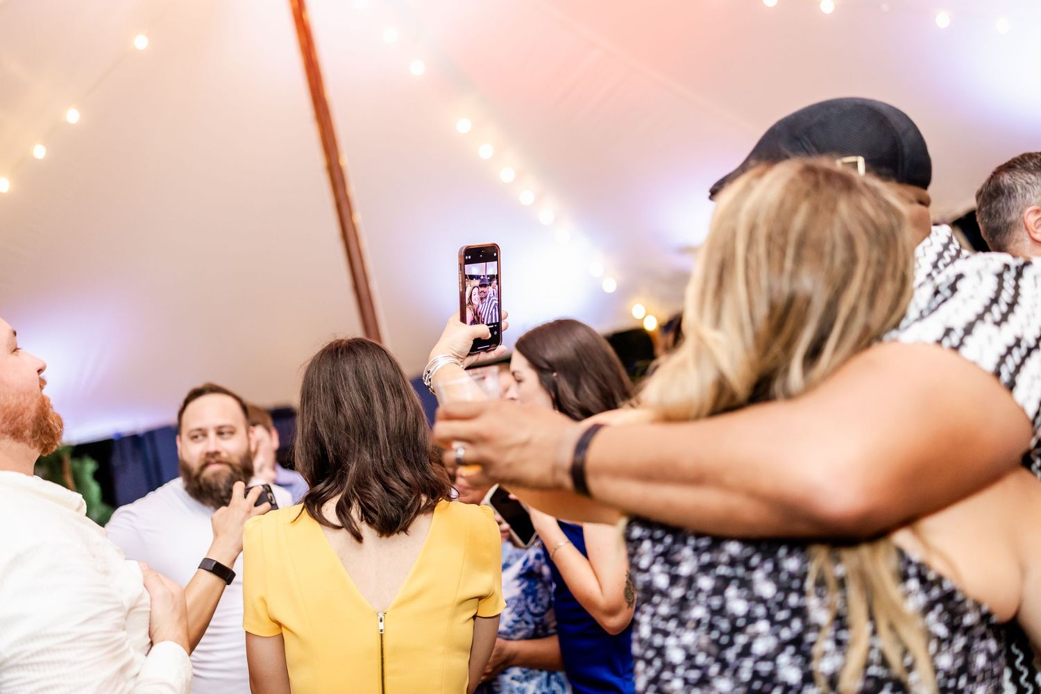 Wedding guests dancing together under warm lighting at reception.