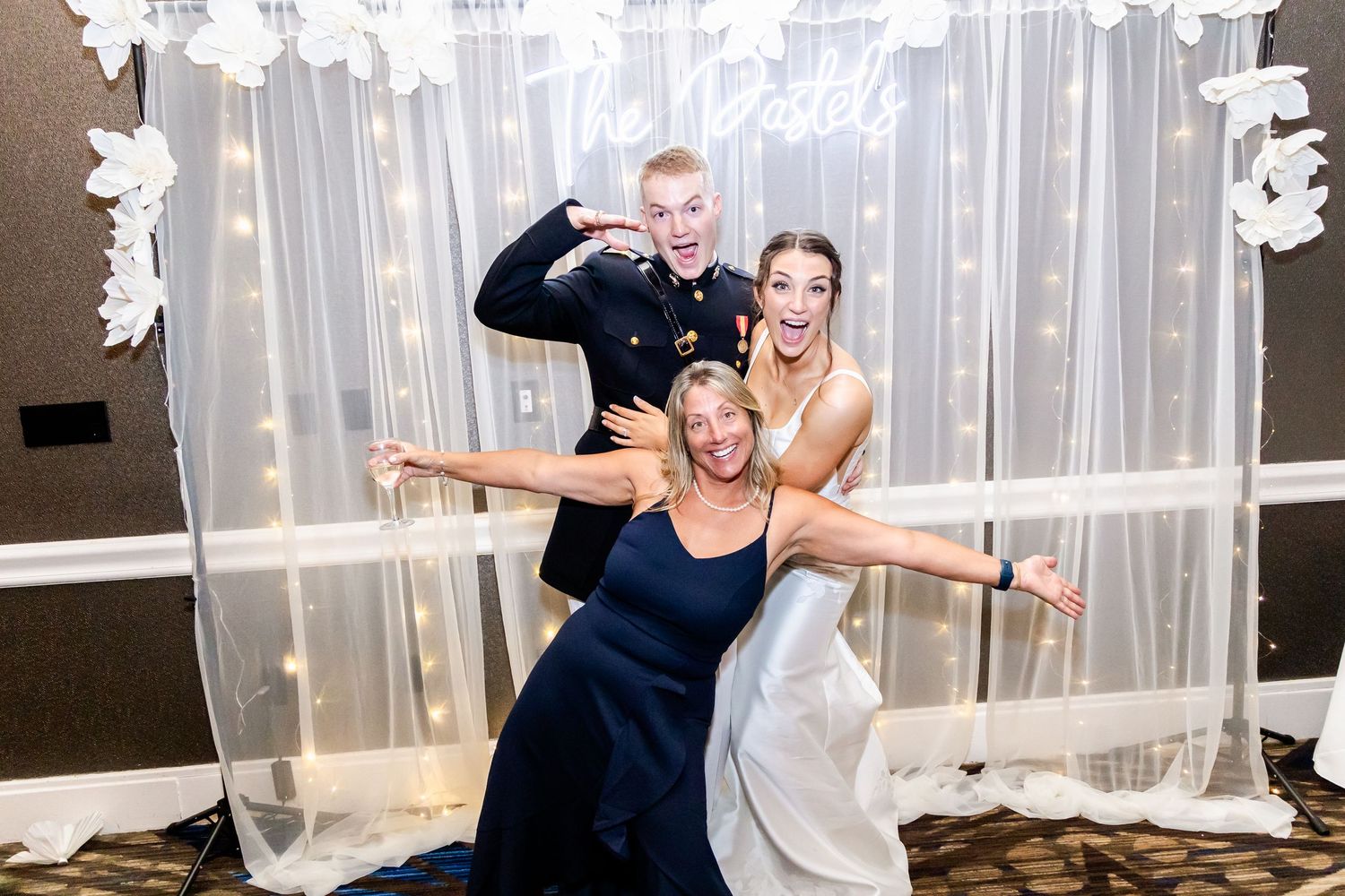 Wedding party celebrates with dance moves against sheer curtain backdrop.