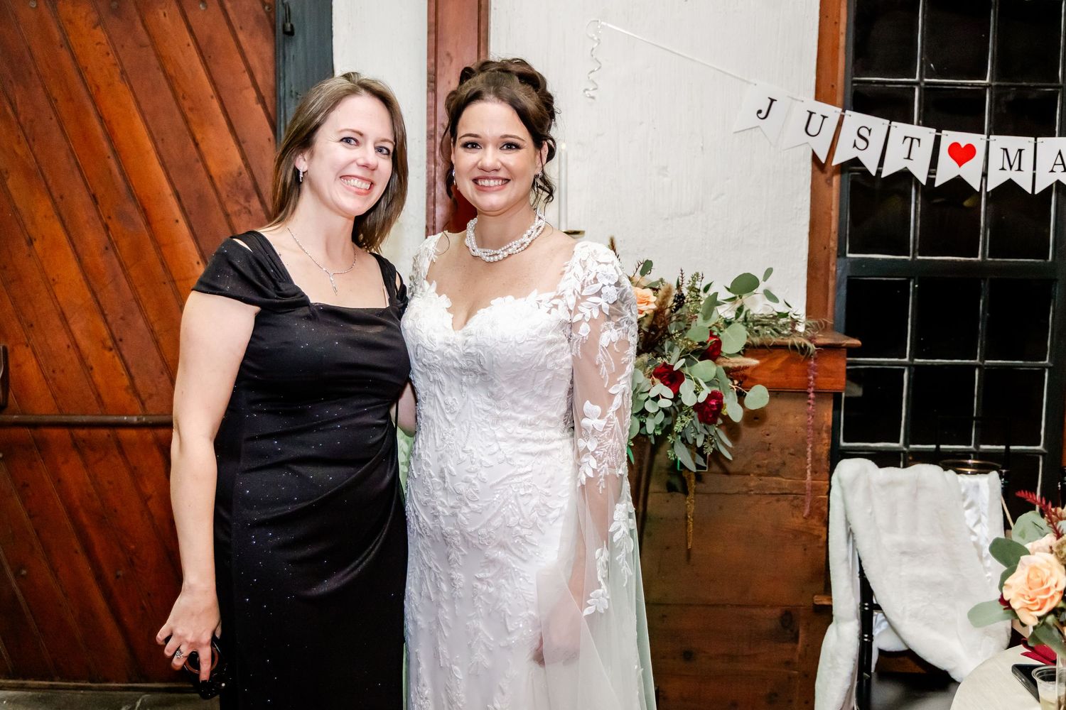 Wedding portrait in front of rustic wooden door with floral arrangements.
