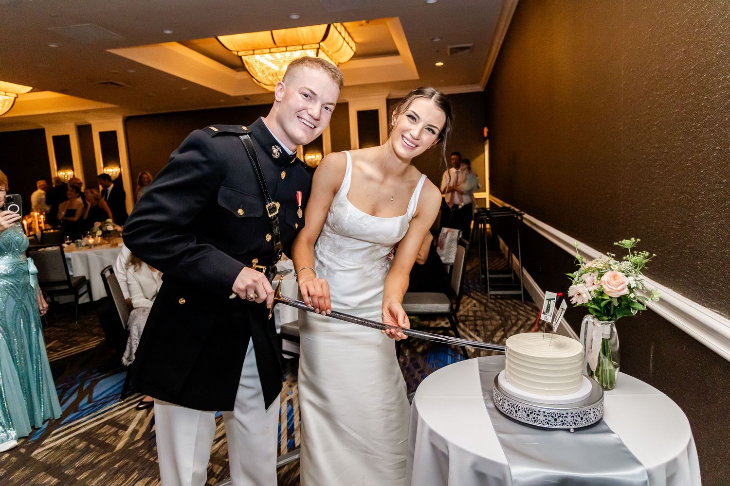 Wedding couple cutting their white tiered cake at the reception.