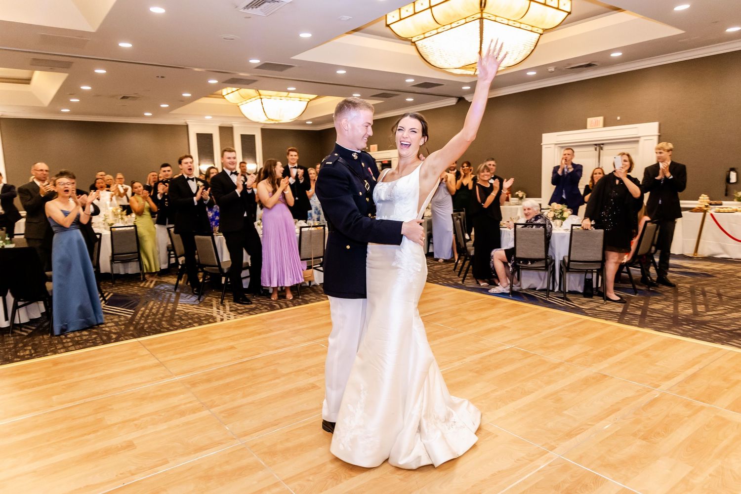 Spacious ballroom wedding reception venue with hardwood dance floor and warm ambient lighting.