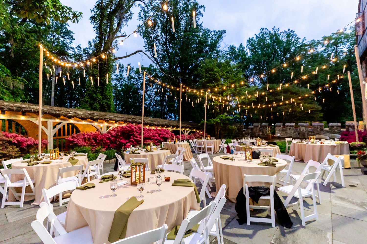 Elegant outdoor wedding reception with string lights and white table settings.