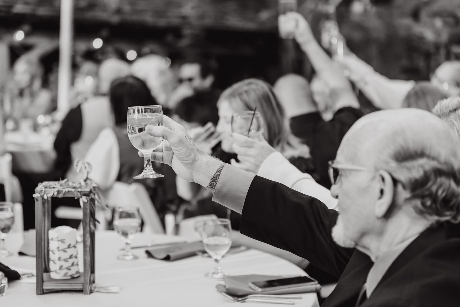 Vintage black and white photo of wedding guests raising glasses in celebration.