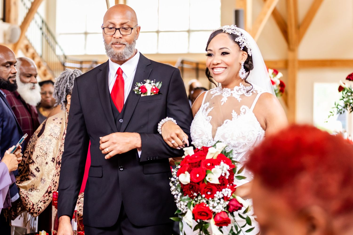 Wedding procession along red carpet with elegant floral decorations.