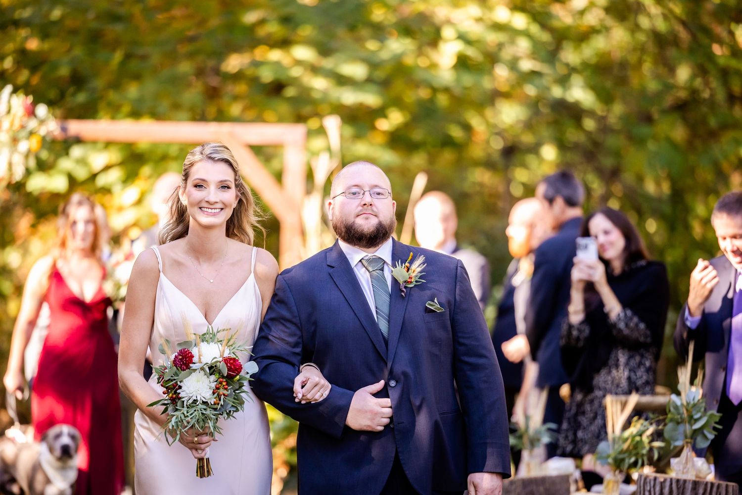Wedding party walking and laughing together outdoors during autumn celebration.