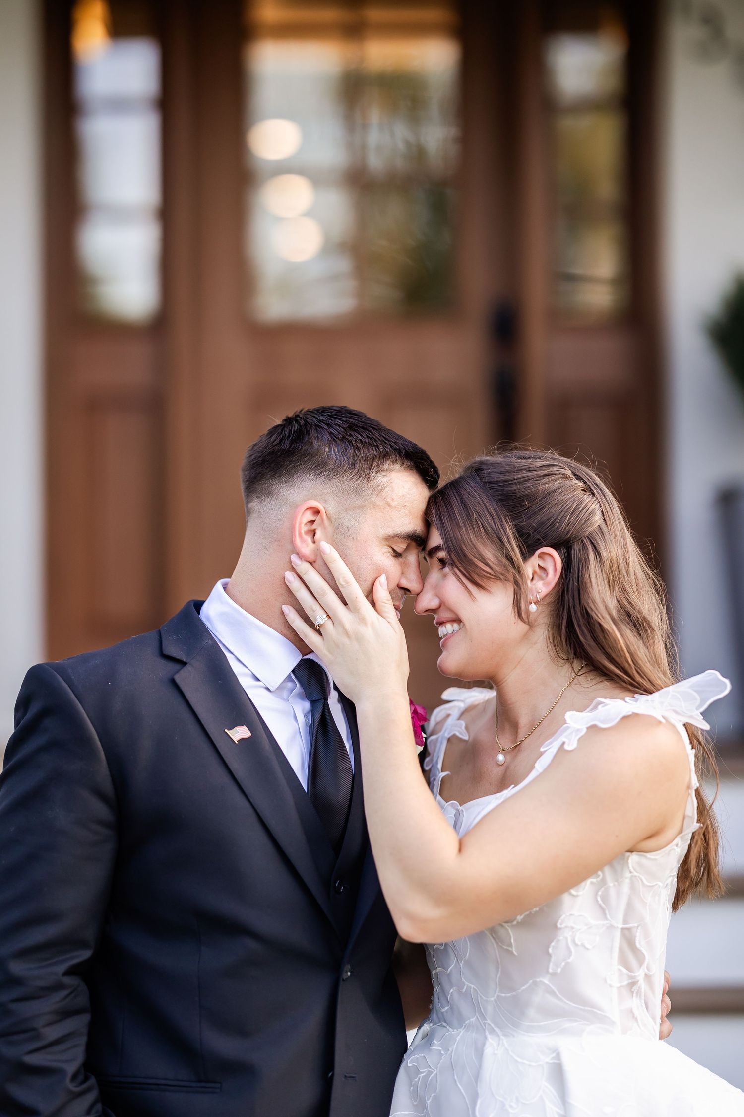 Intimate wedding couple moment captured in front of wooden doors with soft natural lighting.