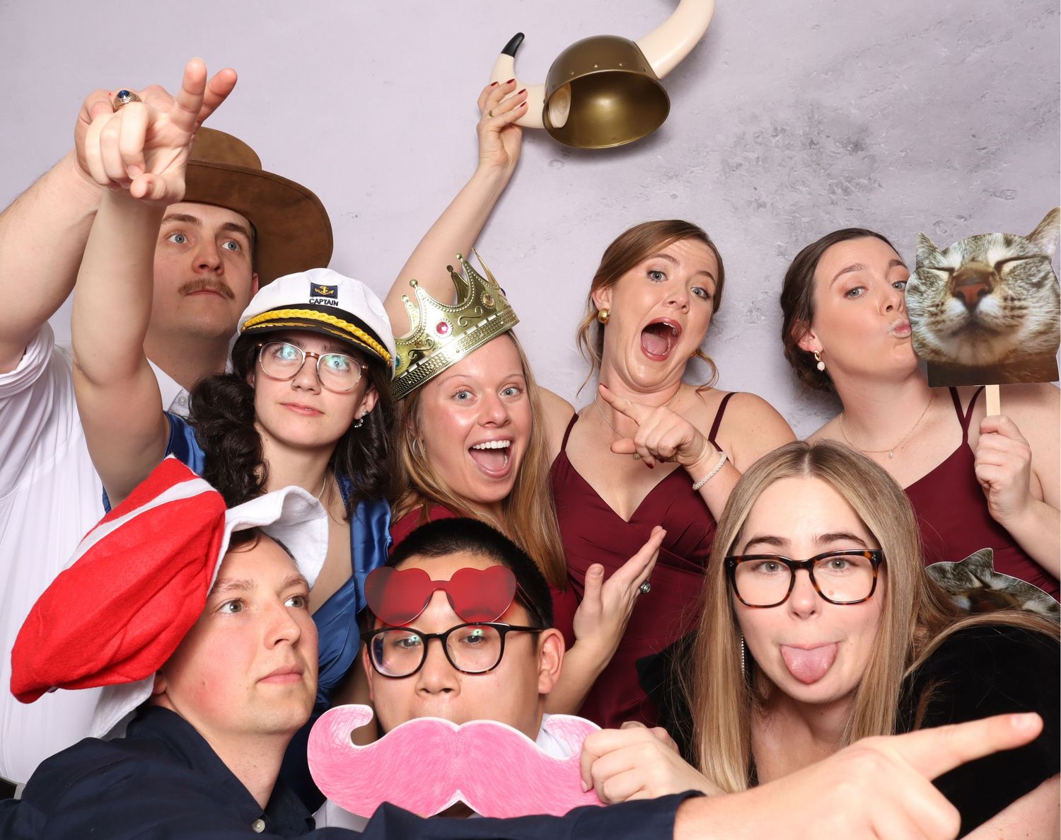 Large group wearing festive props and making silly expressions in a photo booth setting.
