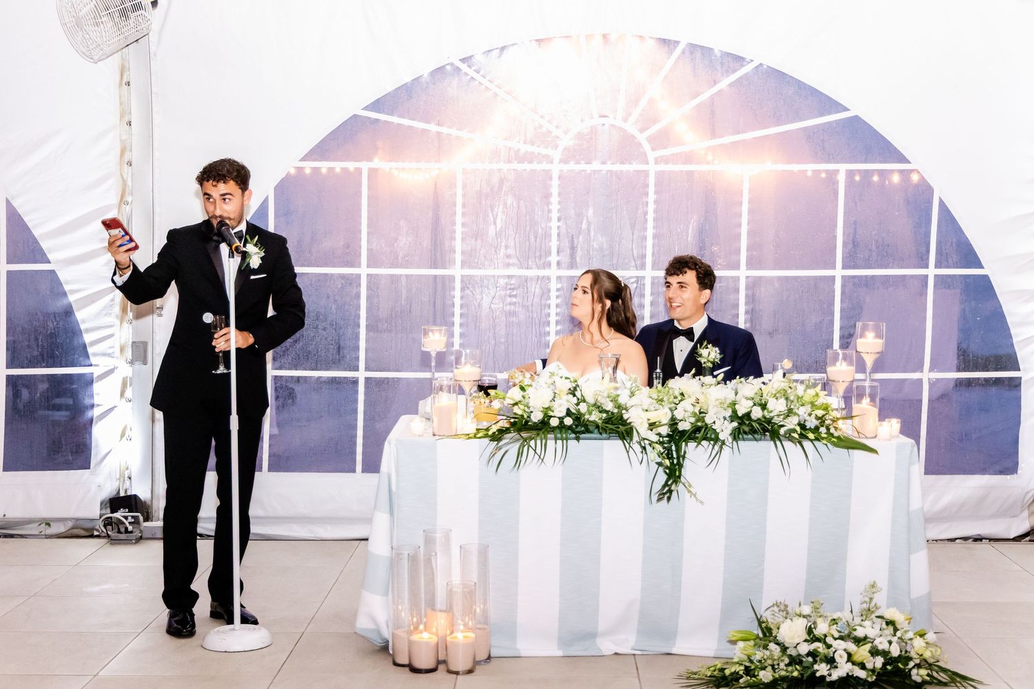 Wedding reception speech being given in an elegantly decorated white tent venue.