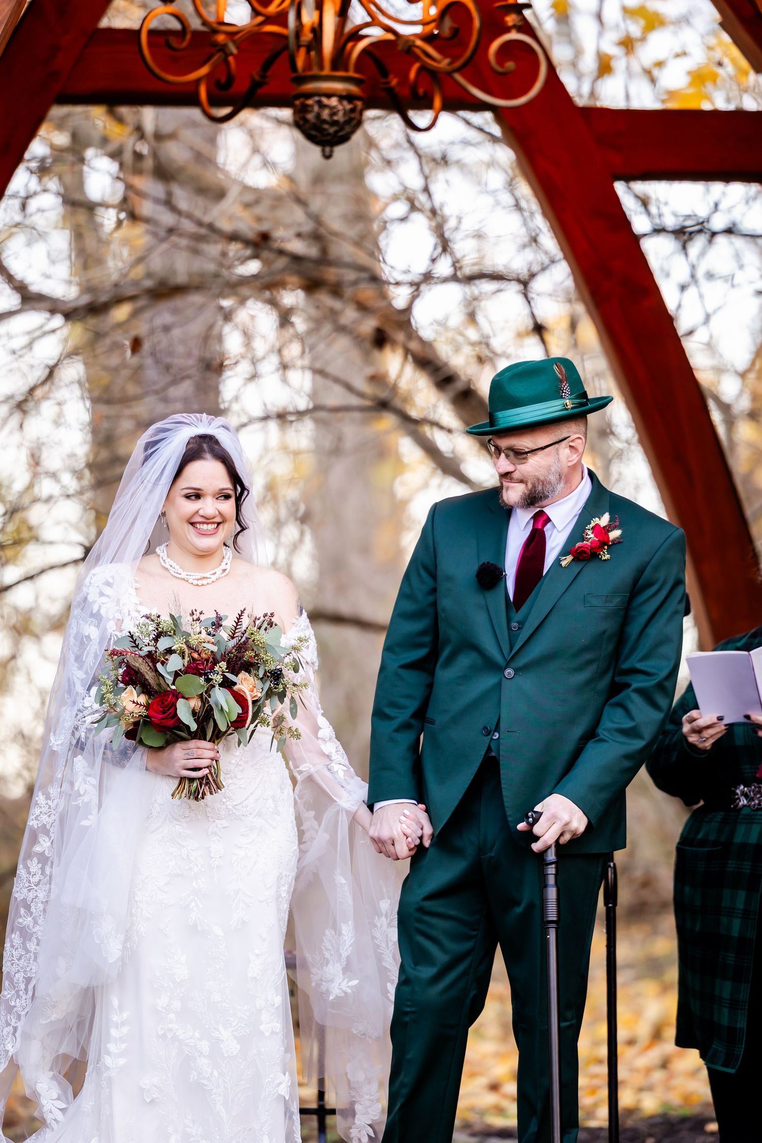 A couple shares a joyful moment during their wedding ceremony under a rustic wooden arch.