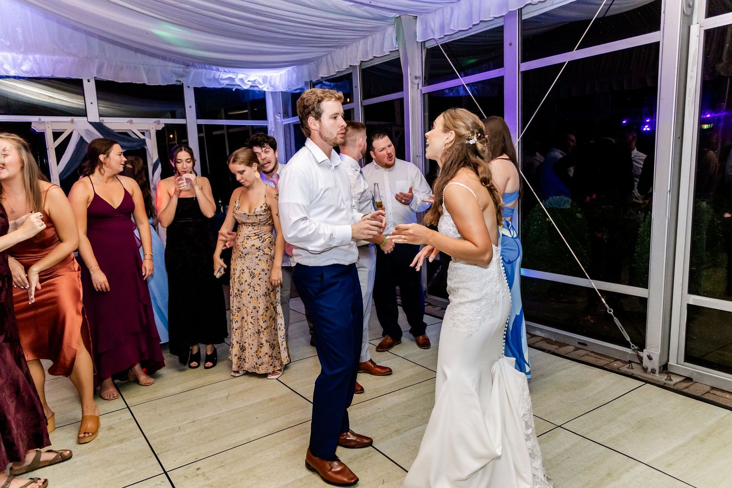 Wedding guests dancing and socializing in an elegantly draped reception space.