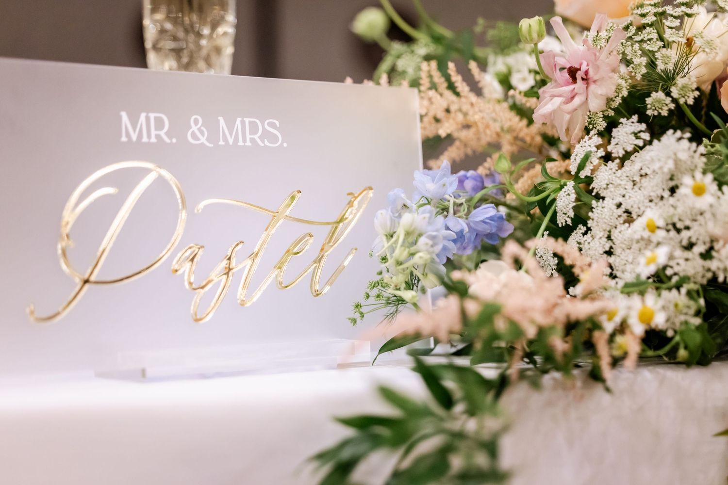Elegant wedding reception decor with gold lettering and floral arrangements.