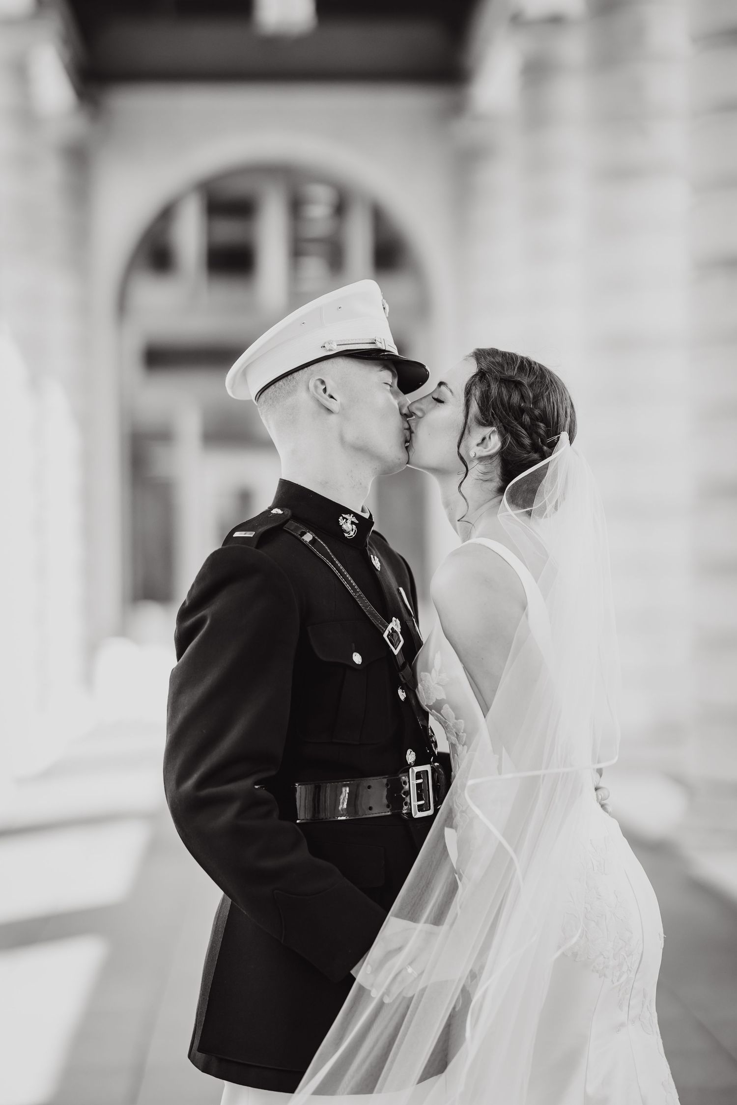 Black and white photo of military couple sharing romantic moment in formal attire.