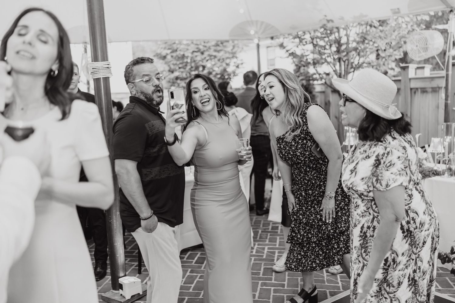 Wedding guests in summer attire dance and mingle at an outdoor reception.