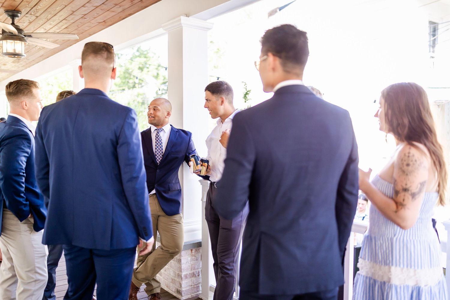 People mingling on a covered porch during an elegant outdoor event.