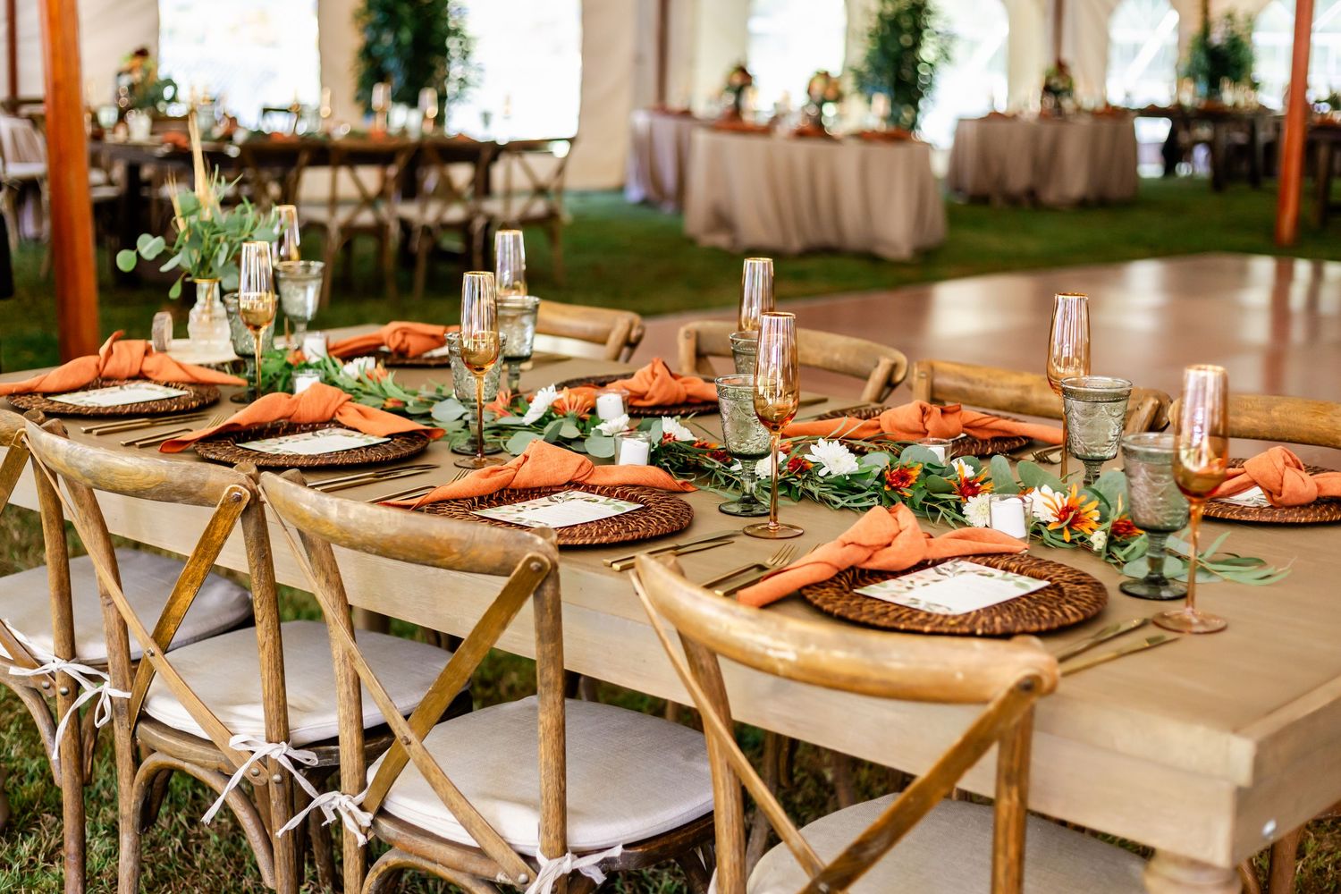Elegant wedding reception tables set with copper chargers and greenery runners.
