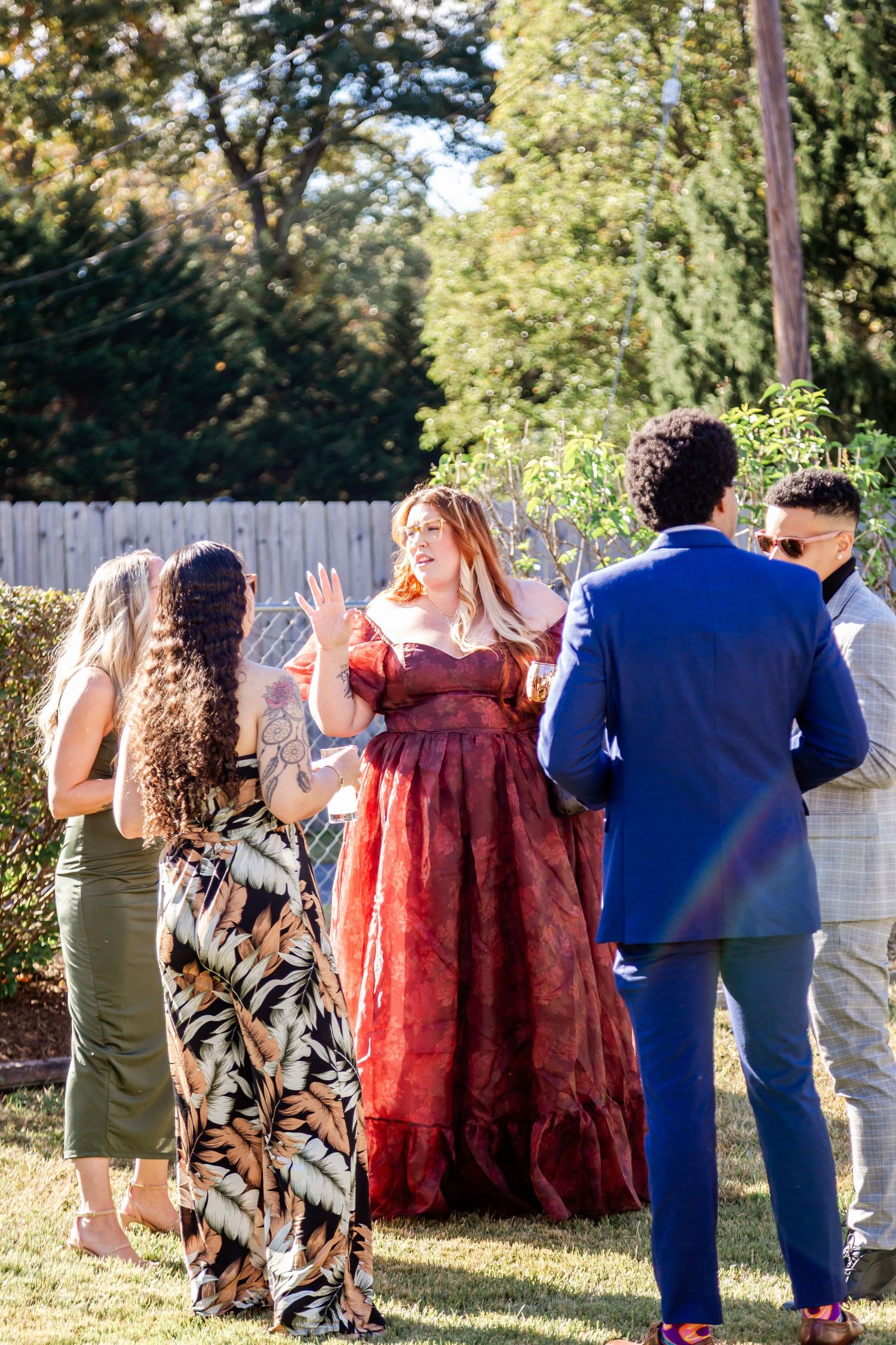Wedding guests dancing and posing together in an outdoor garden setting with trees in the background.