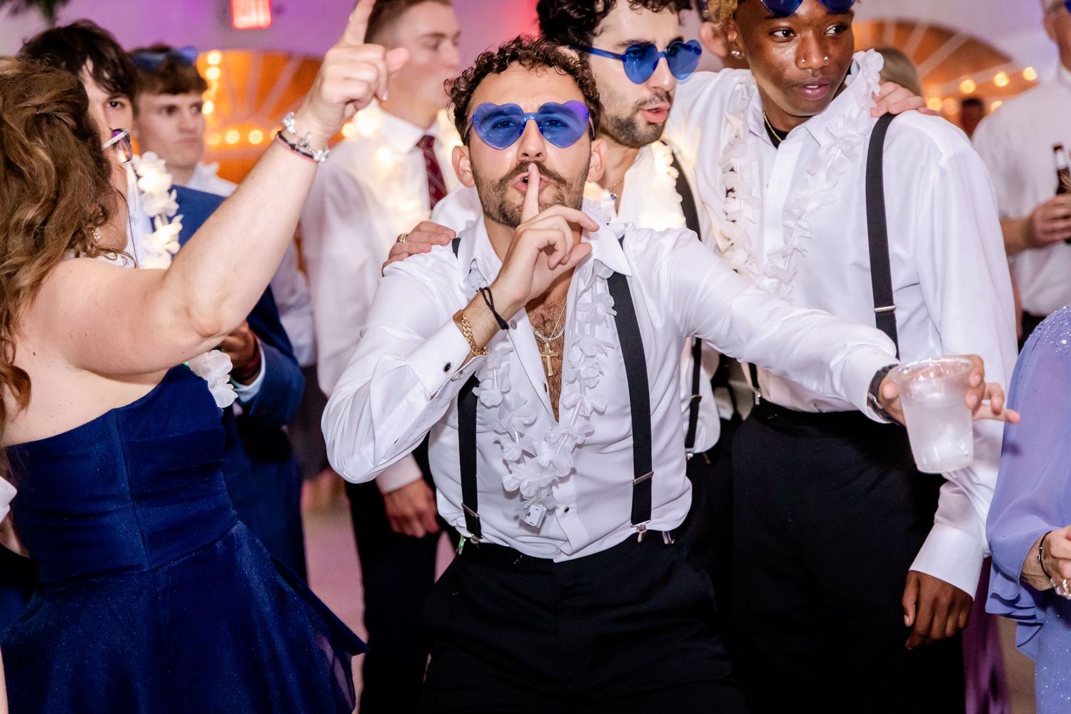 Lively dance floor scene with wedding guests celebrating in formal attire.