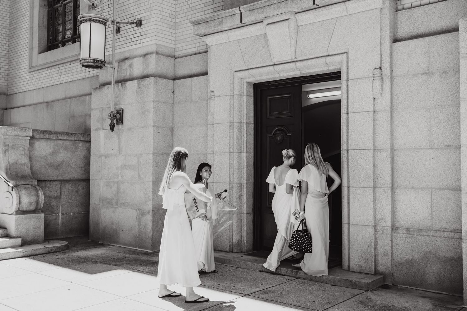 Figures in white ceremonial robes holding candles stand in doorways and steps of a stone church building.