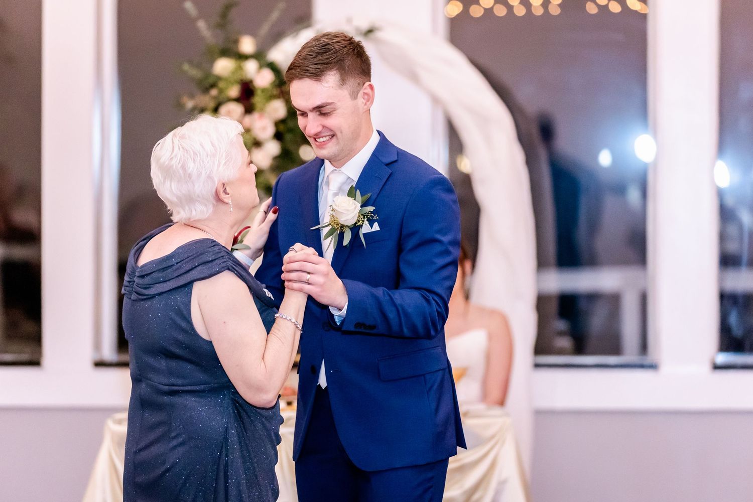 Wedding party dancing and celebrating in a beautifully lit reception hall.