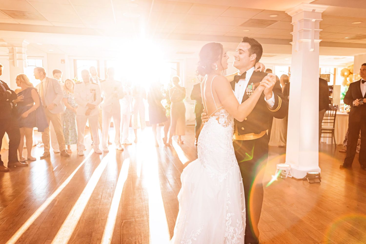 Wedding reception dance floor filled with glowing light and dancing guests celebrating at an indoor venue.