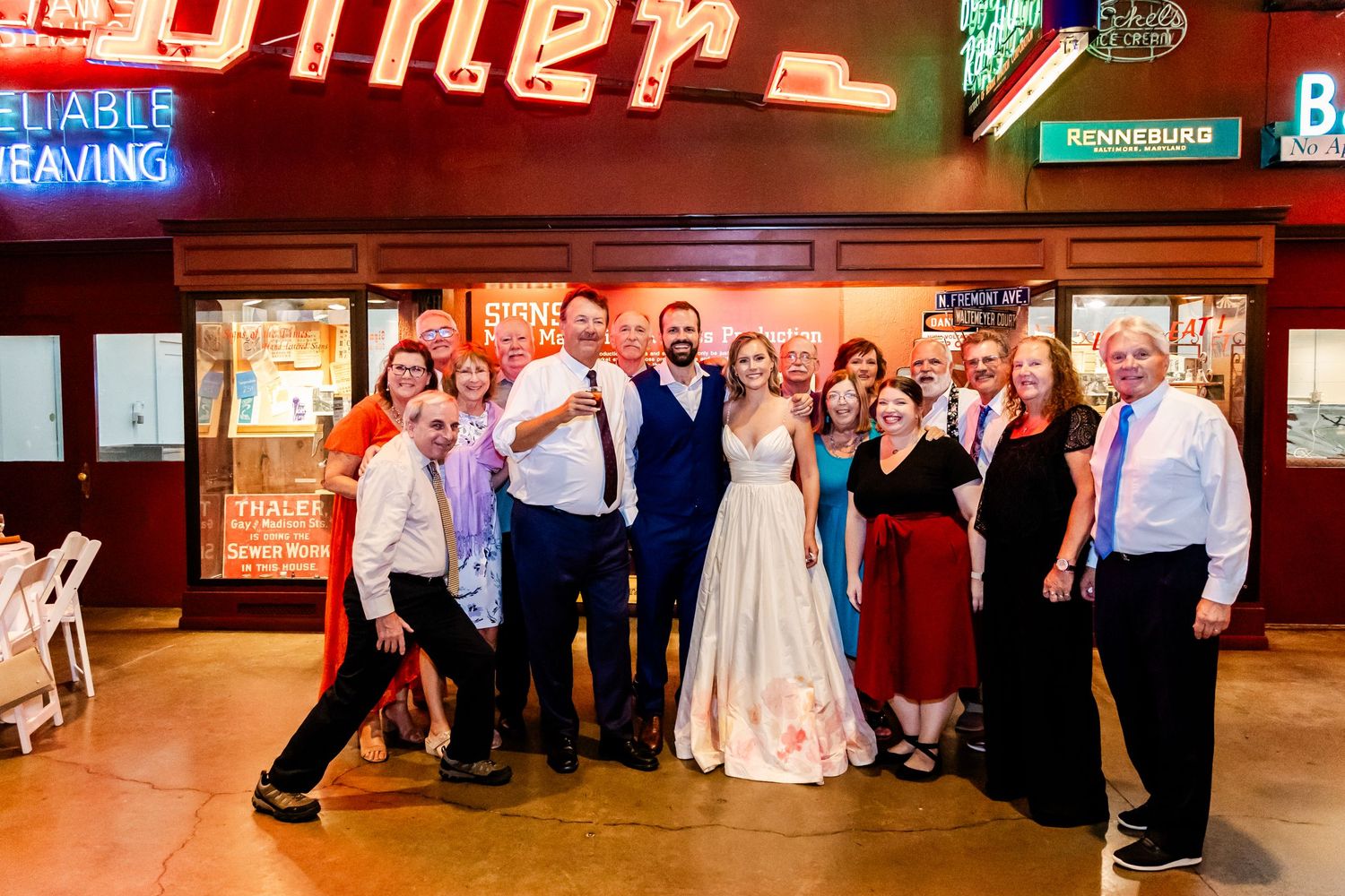 A group poses together for a wedding photo in front of an illuminated retro diner sign.