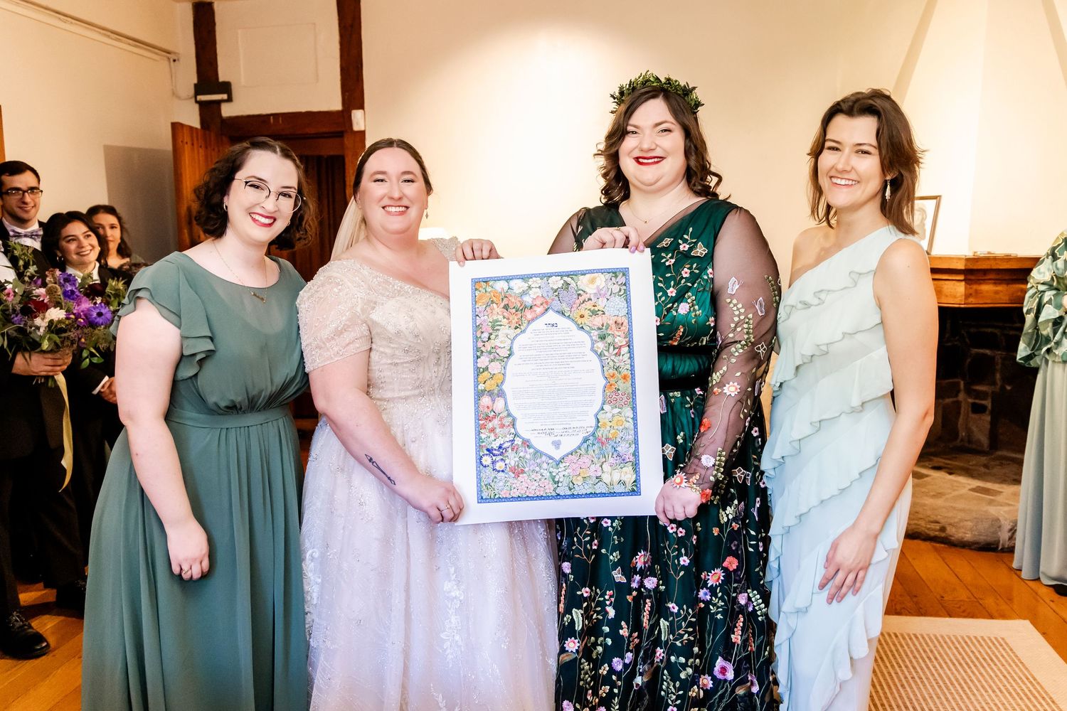 Wedding party members hold up a decorative framed artwork in an indoor venue.