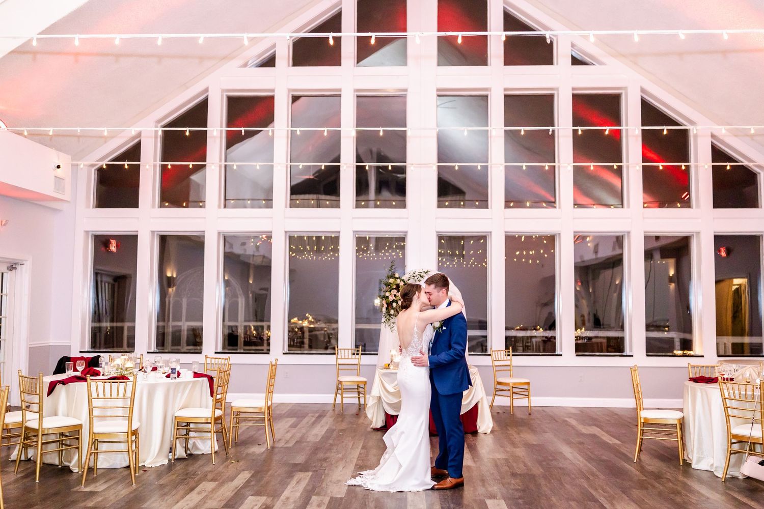 Modern wedding venue interior with large windows, white walls and hardwood flooring.