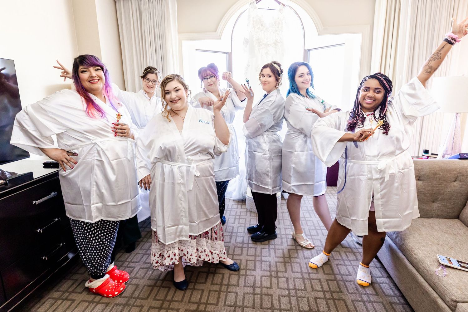 Bridal party in white robes posing playfully in a hotel room.