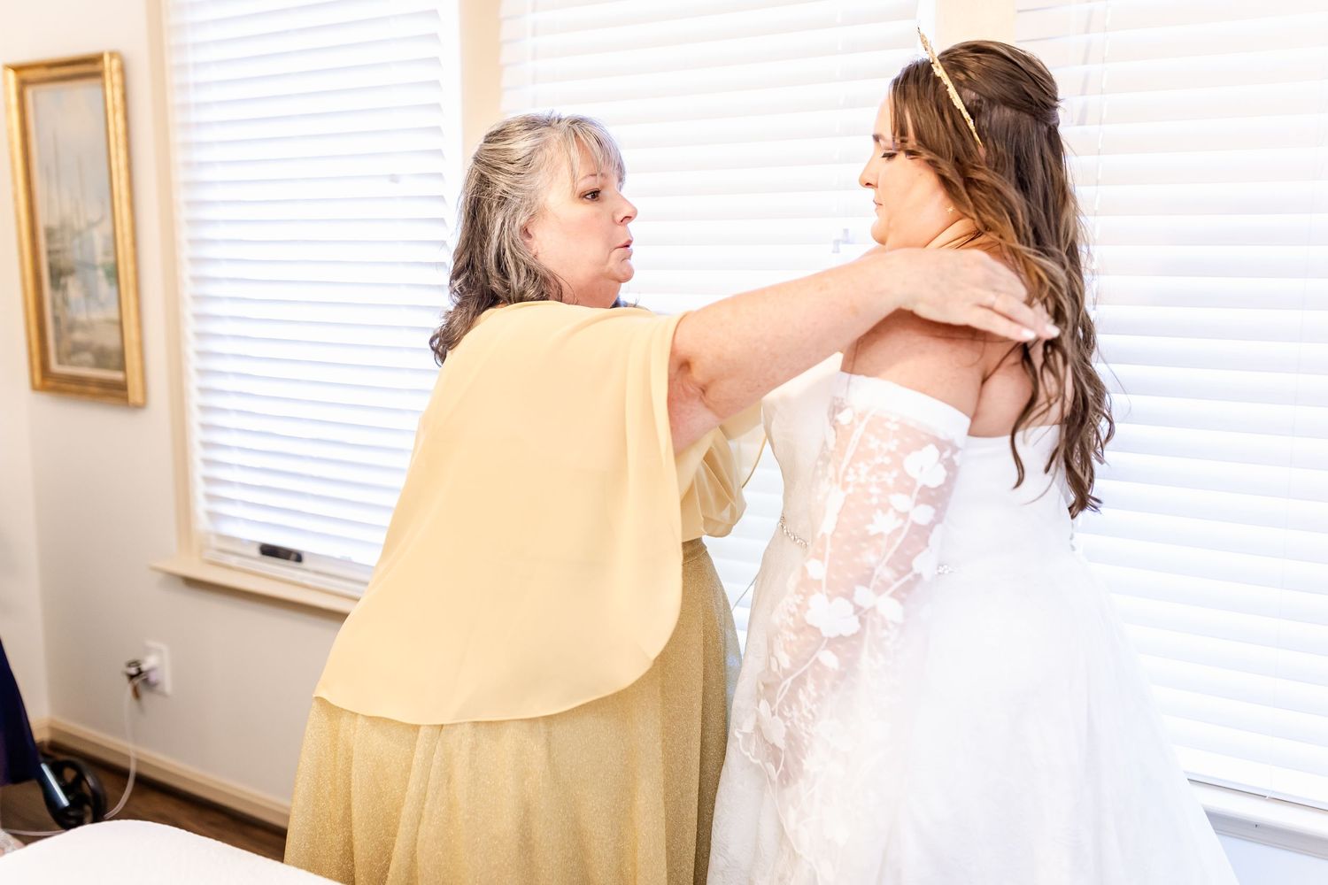 Helper assists with securing wedding dress during final preparation moments.