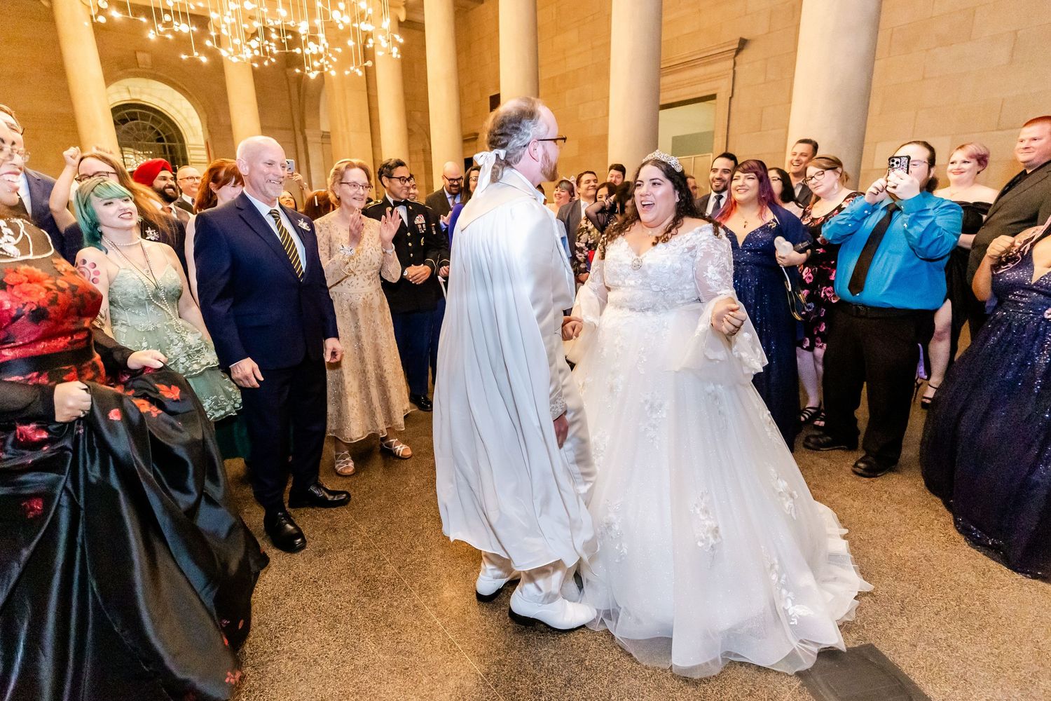 Wedding celebration in an ornate hall with guests watching the couple's first dance.