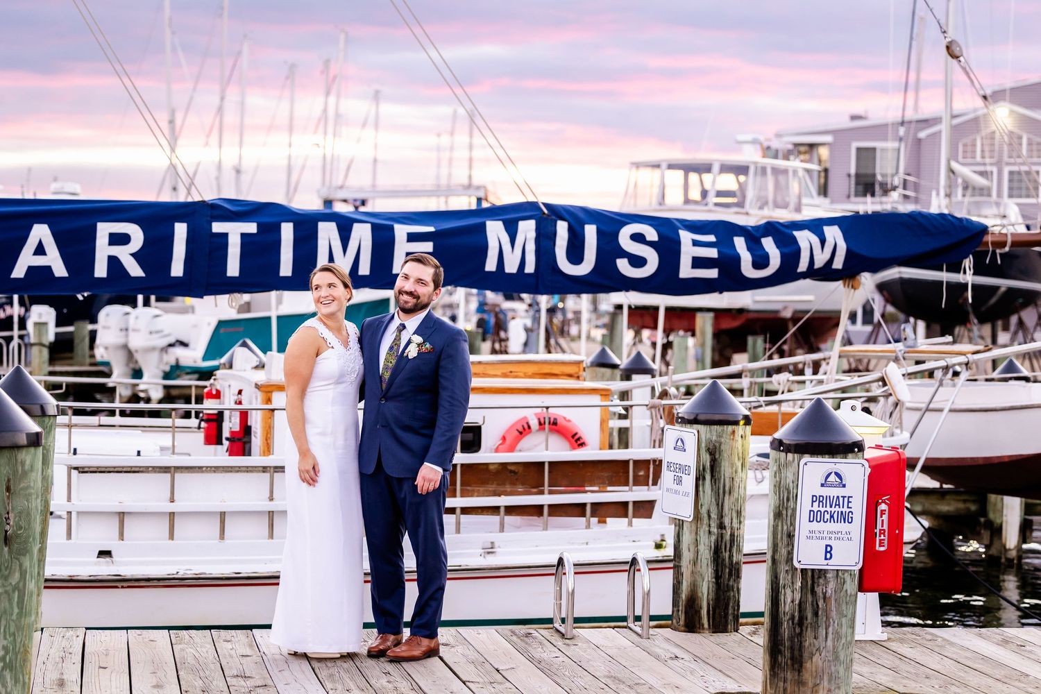 Bride and groom posing on a dock at the Maritime Museum at sunset.