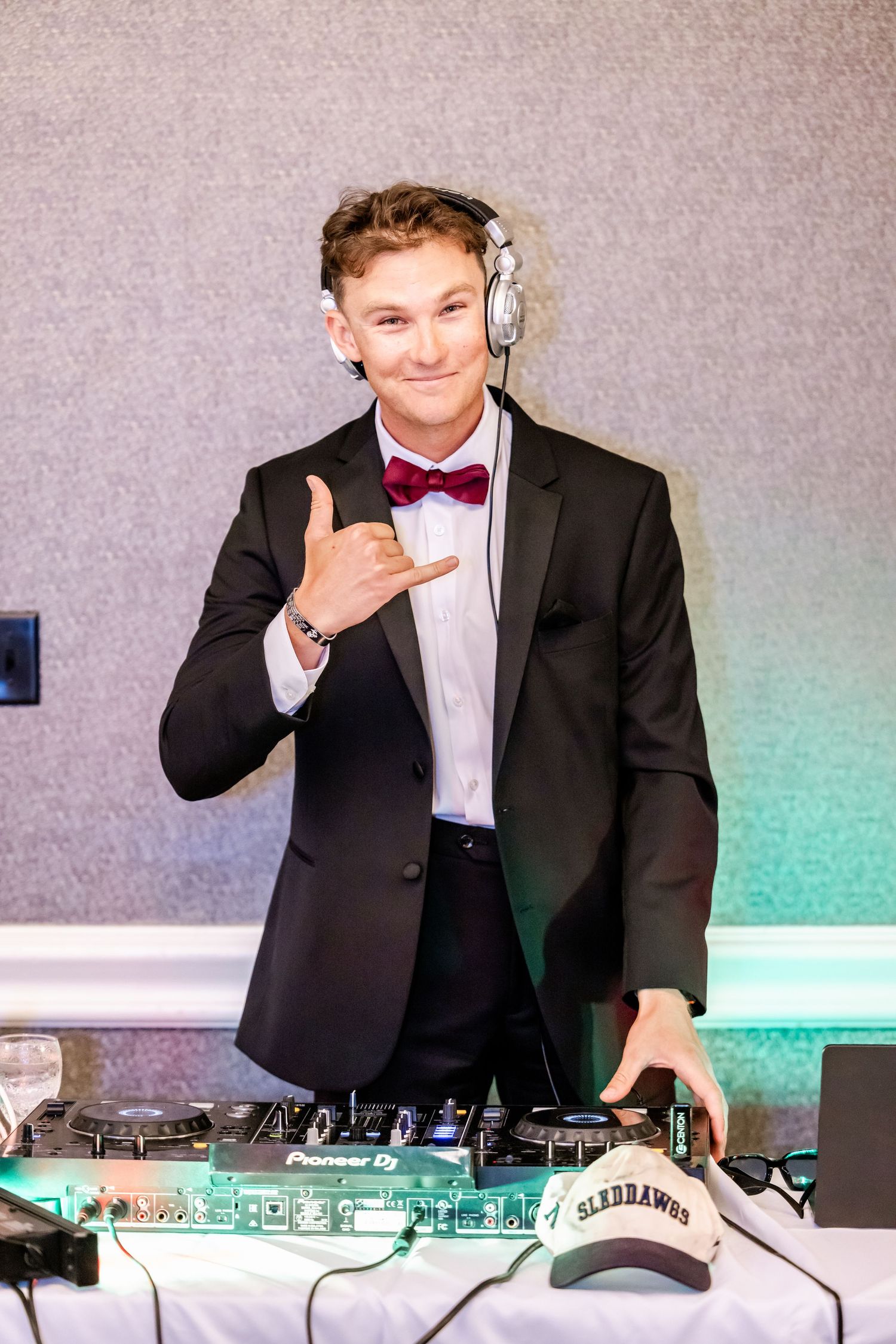 DJ in formal attire works at mixing console during wedding reception.