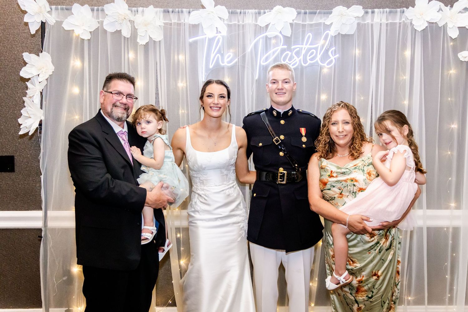 Wedding guests gathered for group photos in front of an illuminated backdrop.