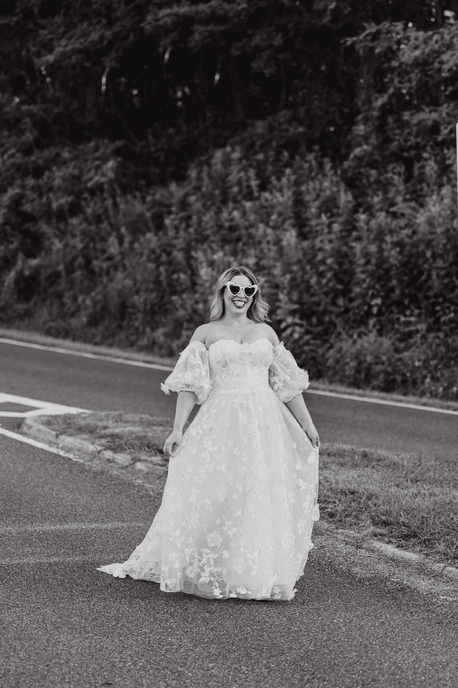 A series of black and white photos showing someone in a flowing white wedding dress walking on an asphalt road.
