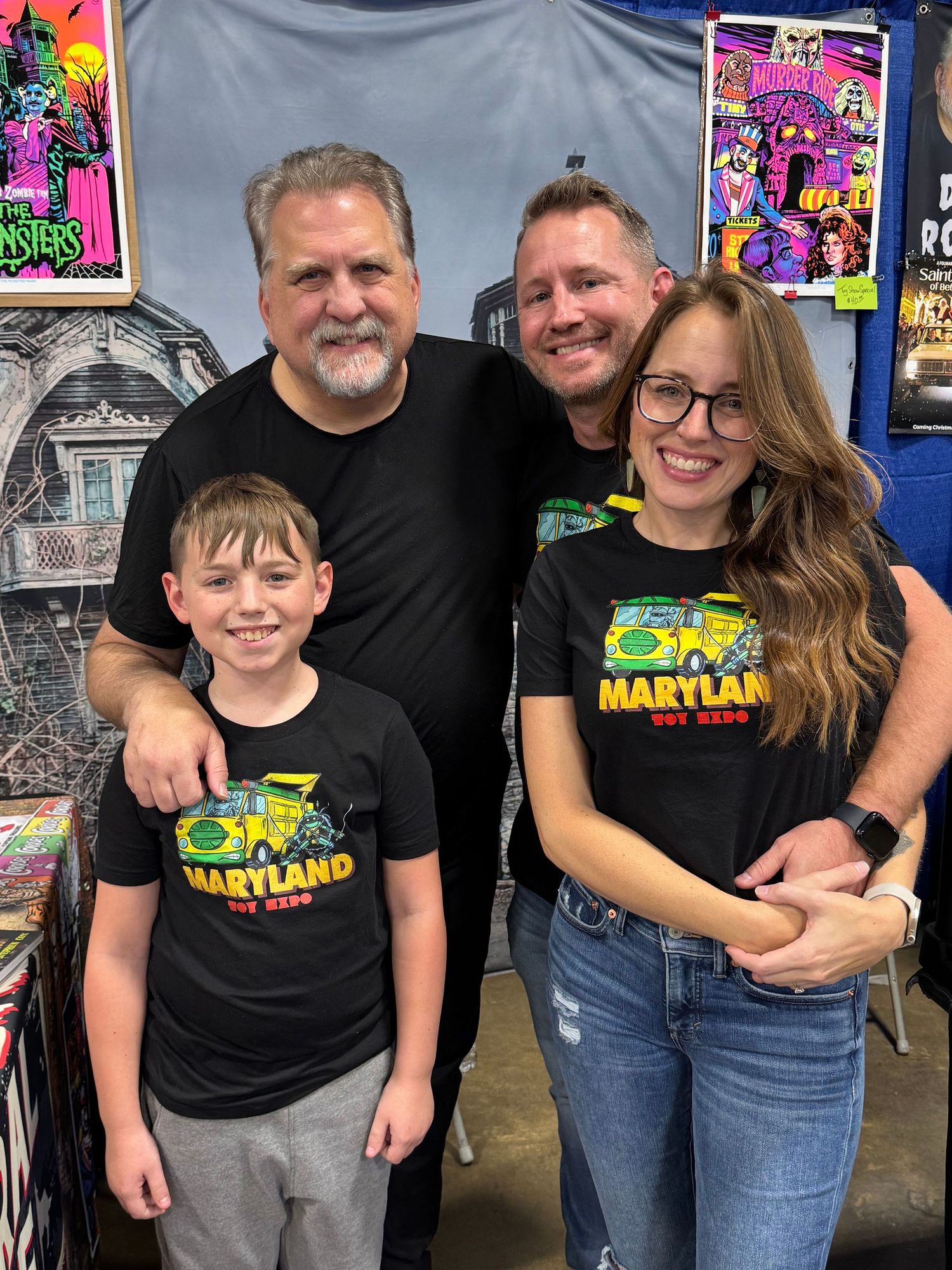 A group wearing matching black Space Martian t-shirts poses together at a comic convention.