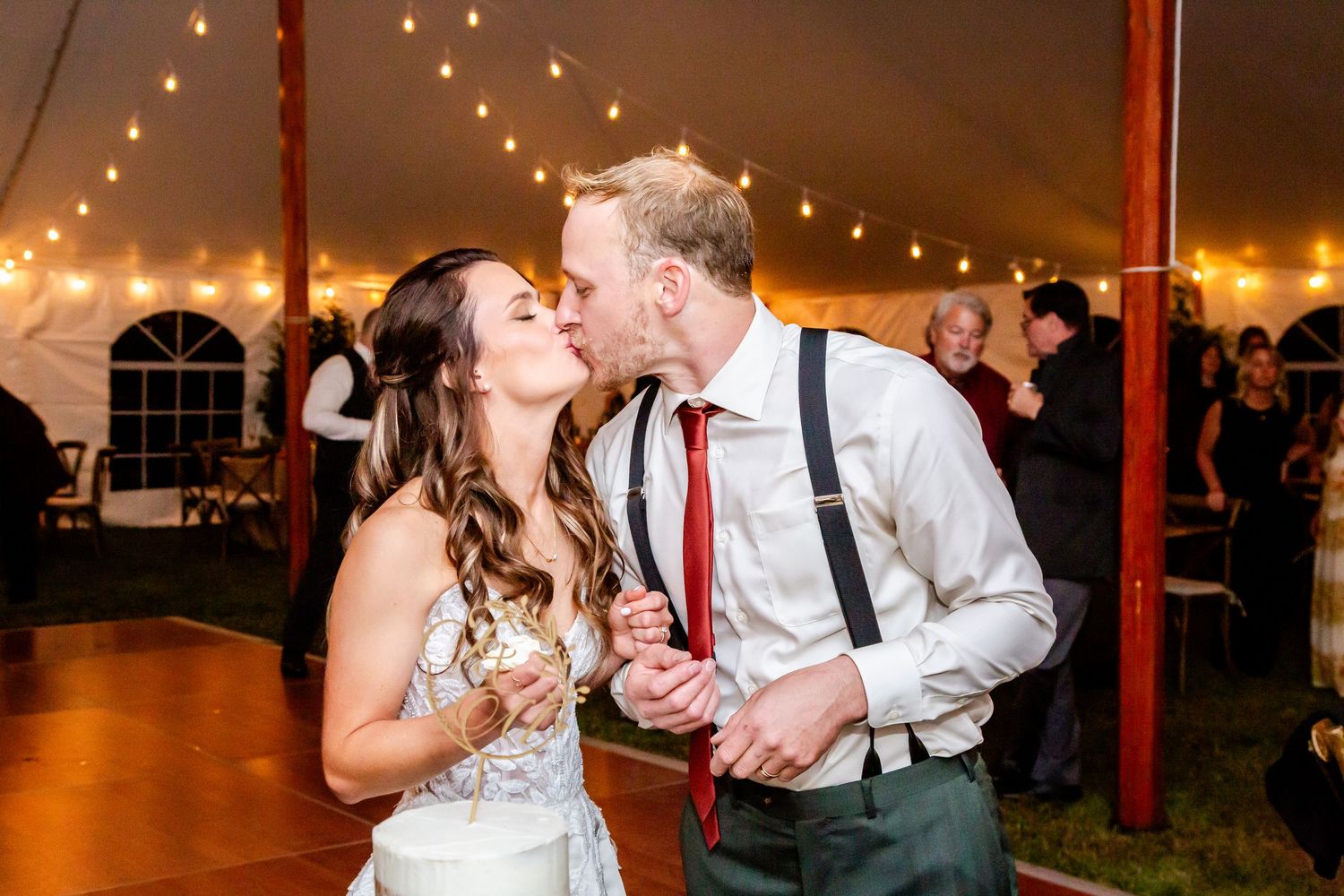 Couple shares a romantic dance moment under warm string lights at an evening wedding reception.