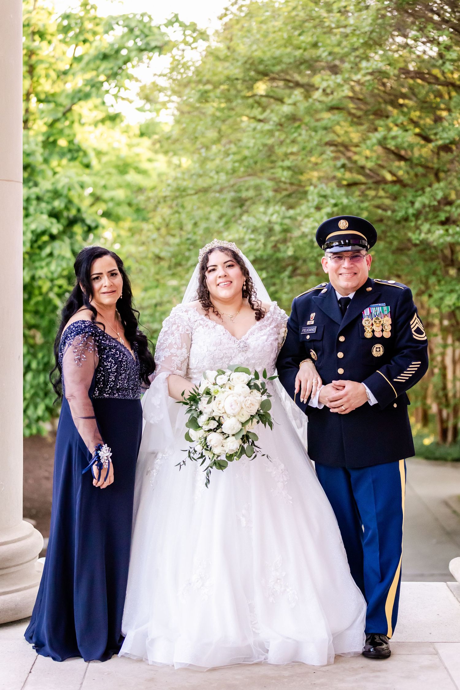 Wedding party poses outdoors with military dress uniform and formal attire.