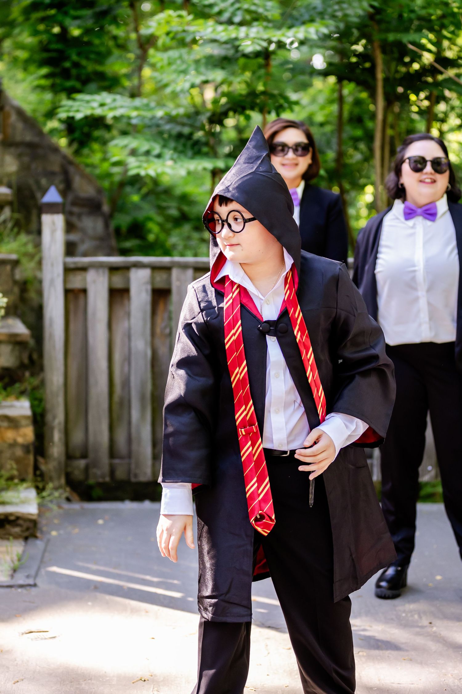 Harry Potter themed wedding party members posing on outdoor stone staircase with floral decorations.