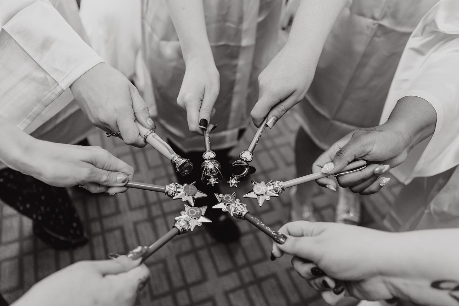 Black and white photo of hands holding sparklers in a circle.