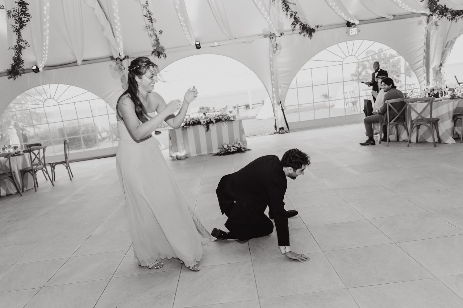 Wedding couple performing their first dance under a decorated white tent.