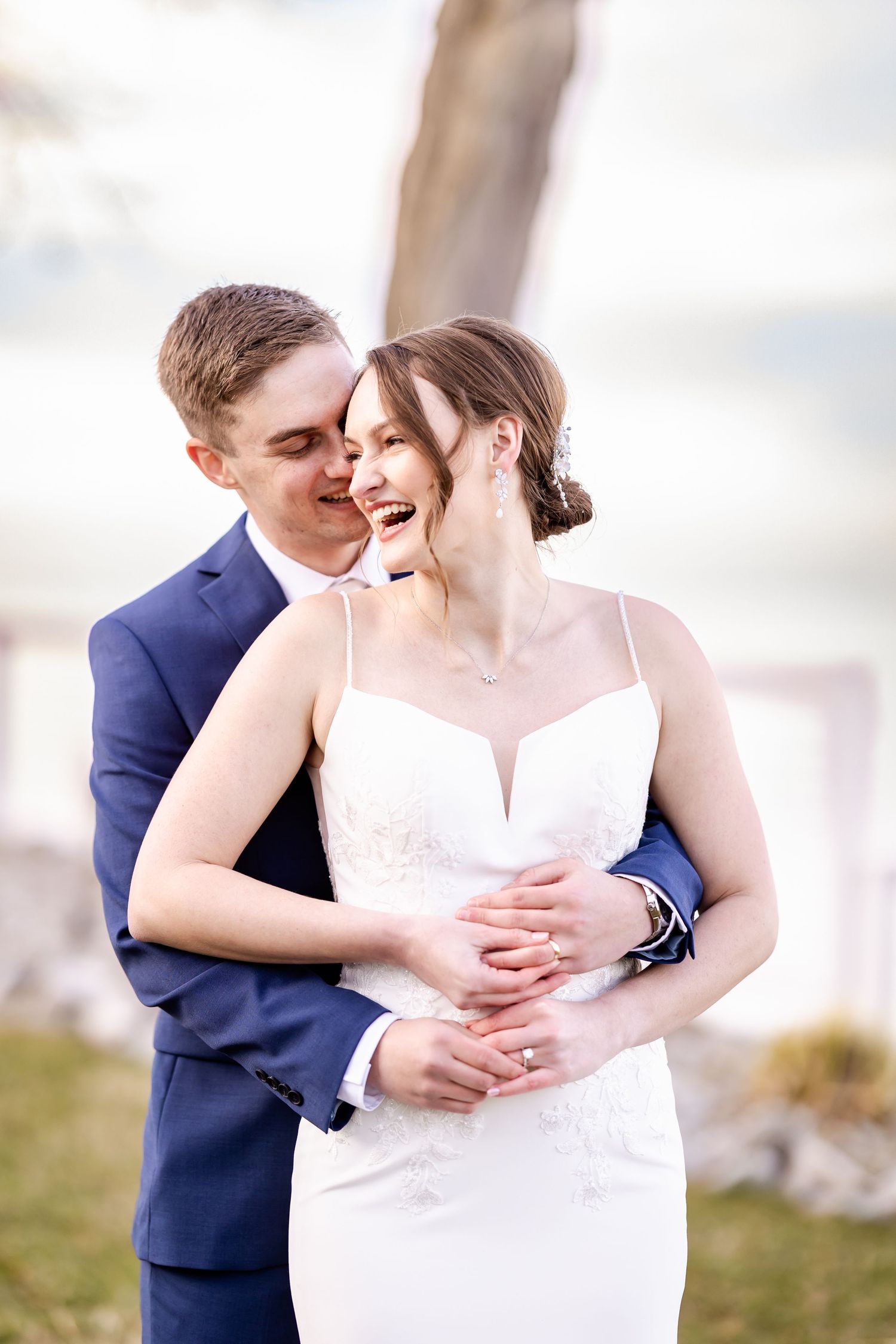 Romantic wedding couple embraces in intimate close-up portraits wearing navy suit and white dress.