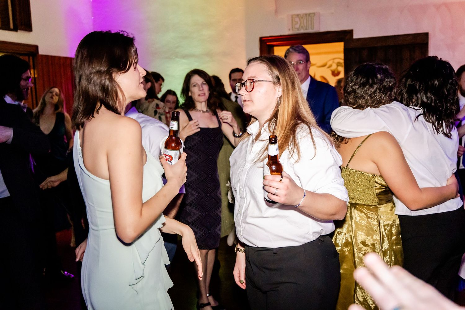 Wedding reception dance party with colorful lighting and guests enjoying the celebration.