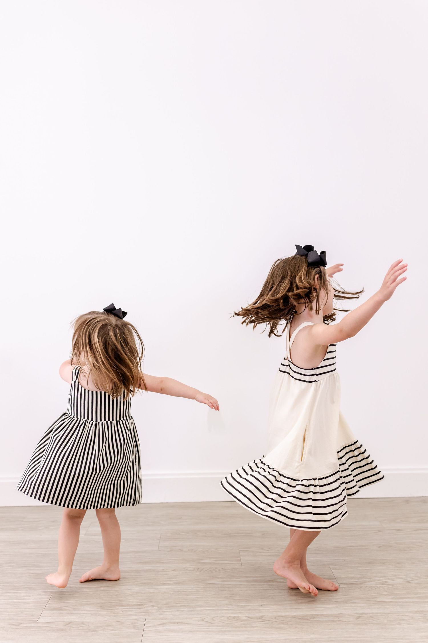 A sequence of five photos showing a person in a striped dress twirling and dancing barefoot on a light wooden floor.