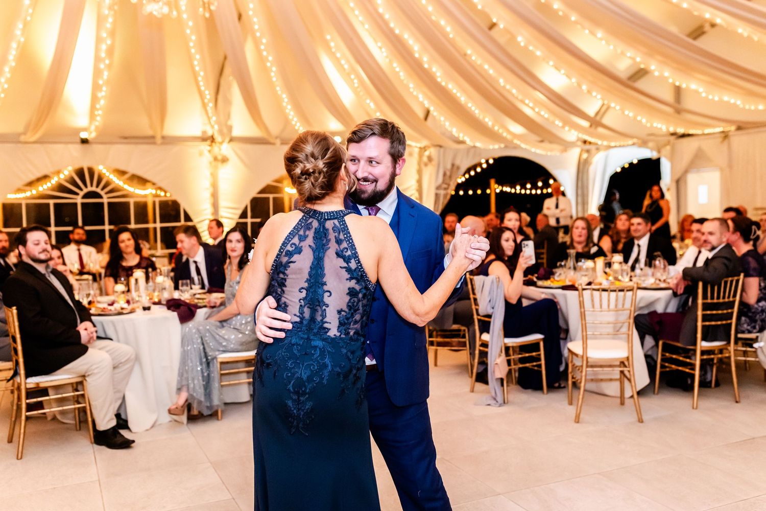 Special dance moment during wedding reception in elegantly decorated tent venue with chandeliers.