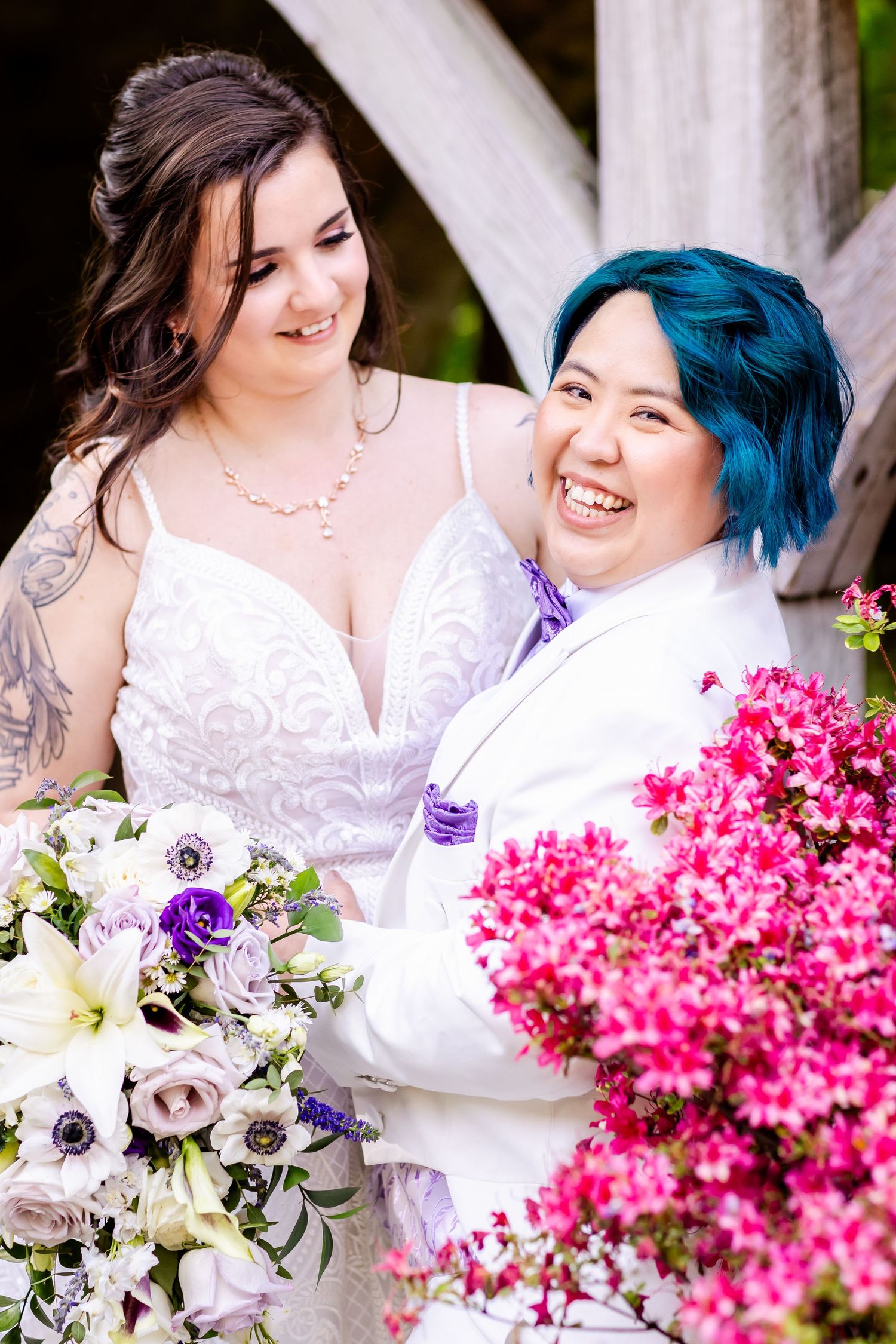 A tender moment captured between newlyweds surrounded by pink flowers and wooden beams.