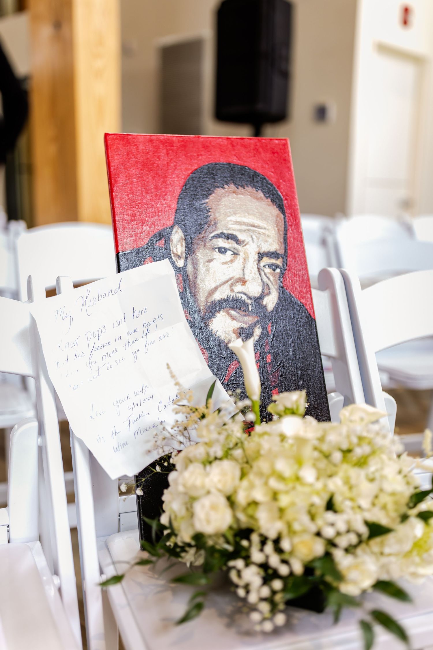 Art portrait display with white floral arrangement on wedding reception table.