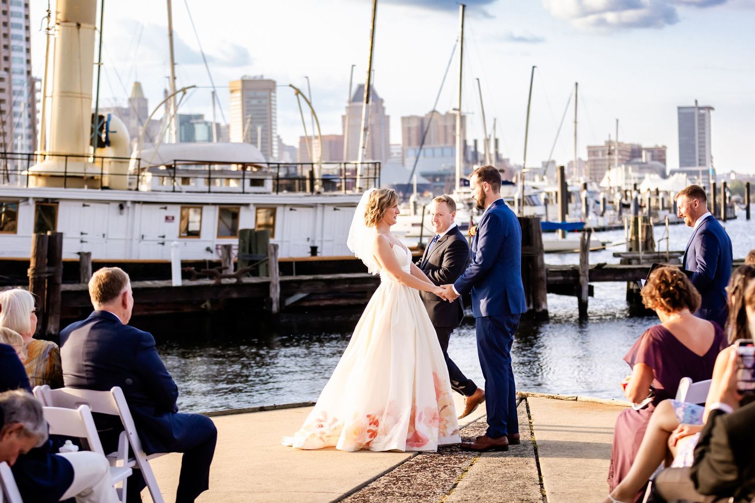 Waterfront wedding ceremony with Baltimore harbor and boats in the background.