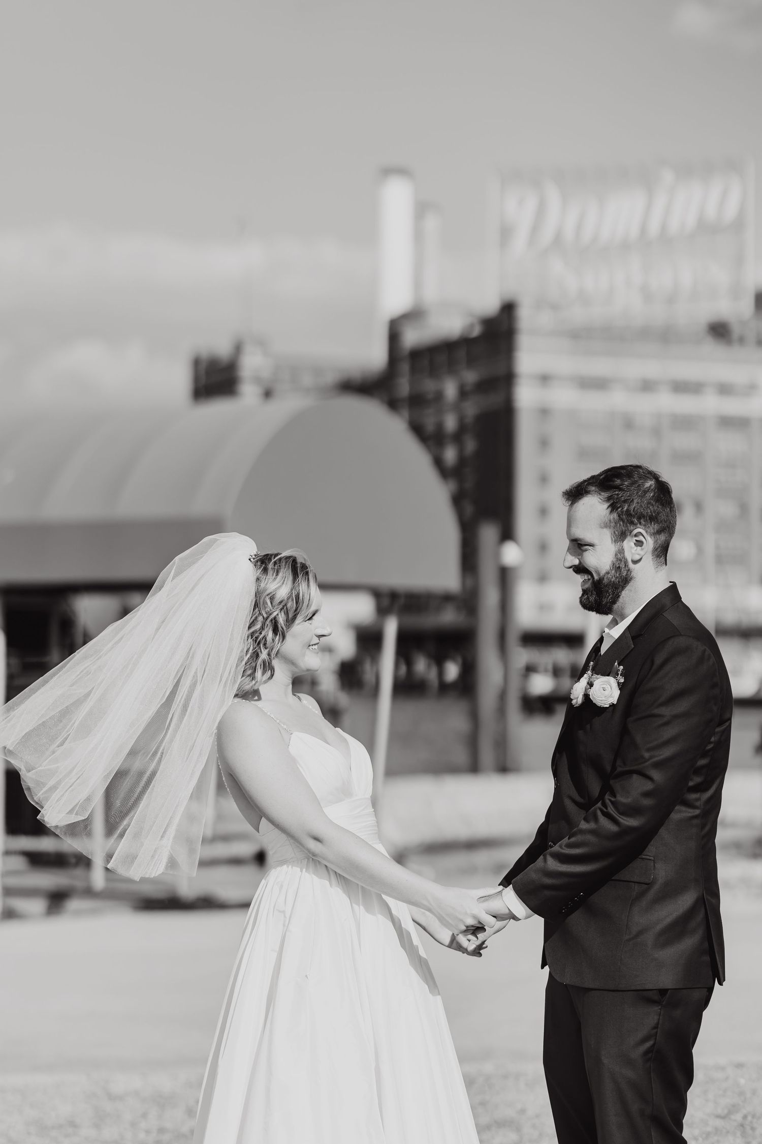 A black and white wedding moment captured in front of a vintage Domino building.