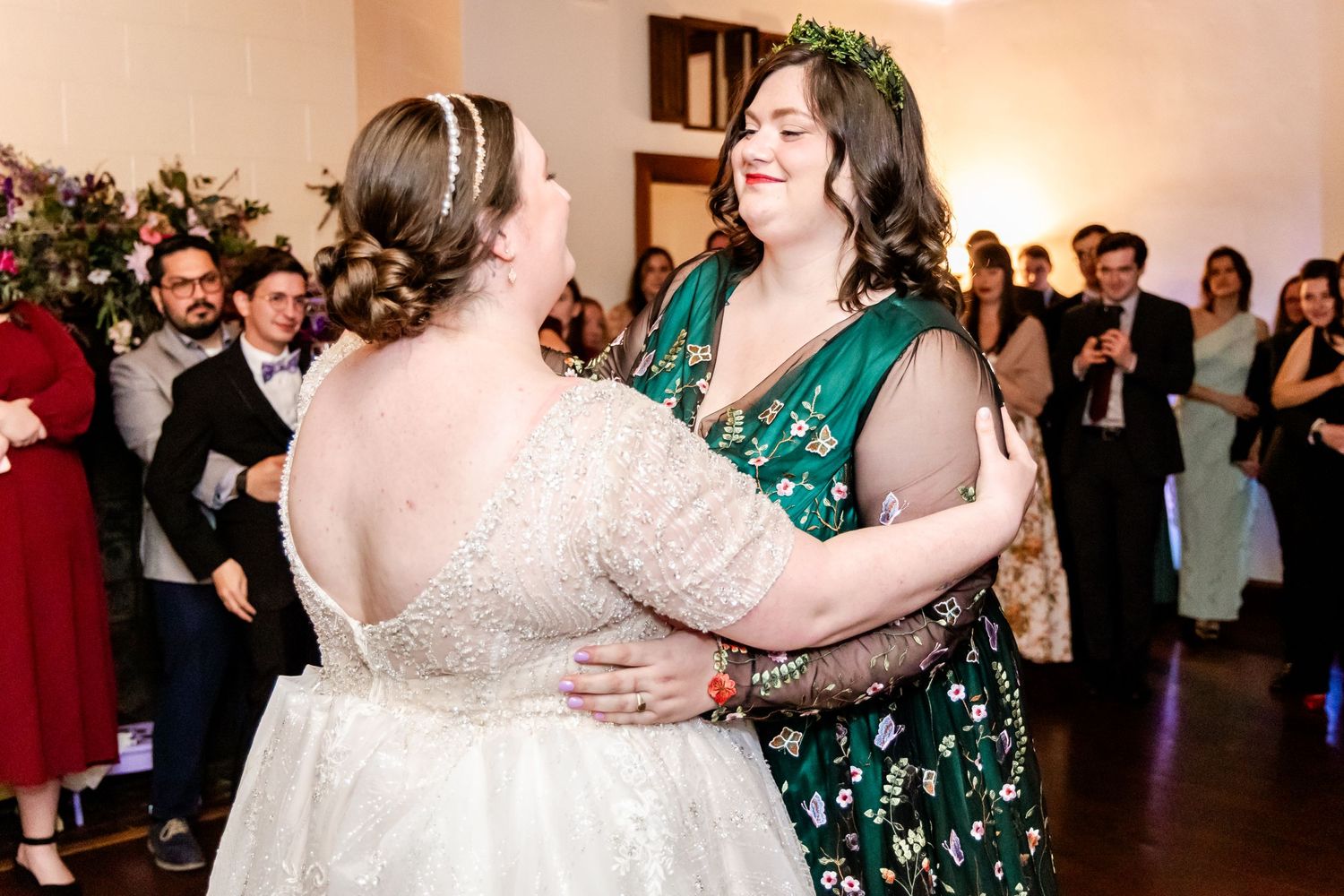 Two wedding guests sharing a dance together at an indoor reception venue.