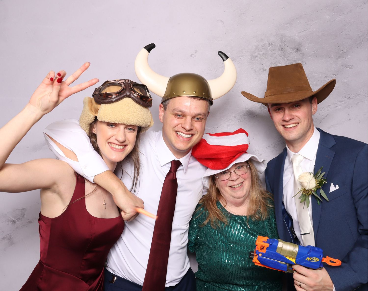Group of people in formal attire posing with props and hats in a photo booth strip.